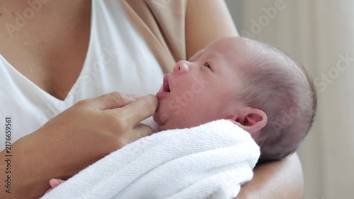 Close up of a cute newborn infant resting comfortably in mother's embrace, showing concept of maternity, childcare, postpartum wellness, and beautiful bond of motherhood.