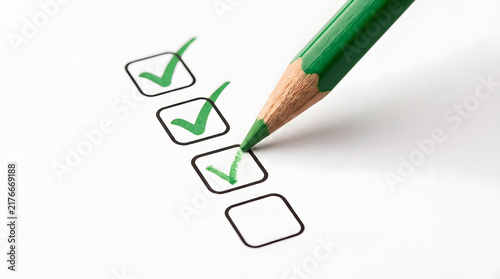 Green pencil with a wooden tip marking green checkmarks in a row of empty checkboxes on a white paper background featuring checked, tick, tick mark, form, survey, list, task, completion and approval