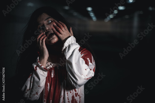 Obraz na plátne Halloween woman, scary costume, bloody hands holding face, white glowing eyes, s