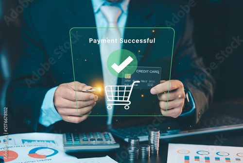 Businessman holding credit card and coins with payment successful hologram interface, mobile banking and online shopping checkout concept.