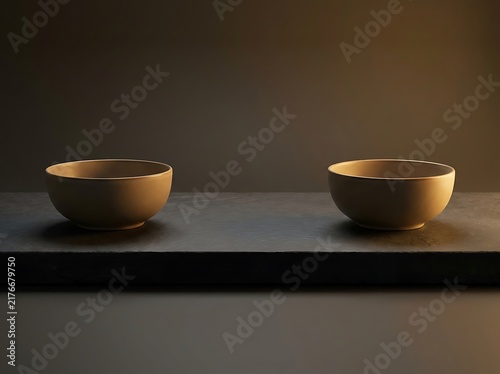 A minimalist studio shot of two empty ceramic bowls on a slate surface representing the concept of amicable divorce