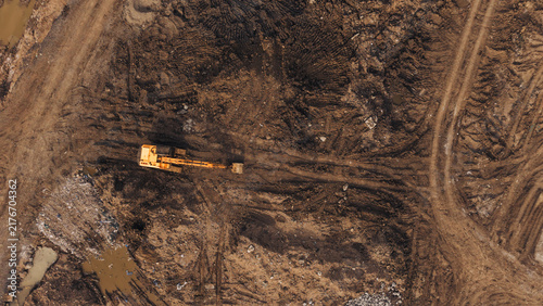 Obraz na płótnie Excavator plowing dark churned soil at land clearing construction site industria