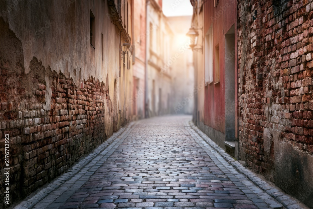 Obraz premium Serene Passage Through an Atmospheric Old Town Street with Textured Walls and Warm Light
