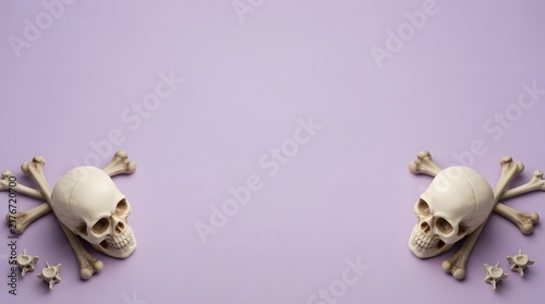 Two human skulls with bones arranged on a light purple background for a creative halloween holiday celebration design