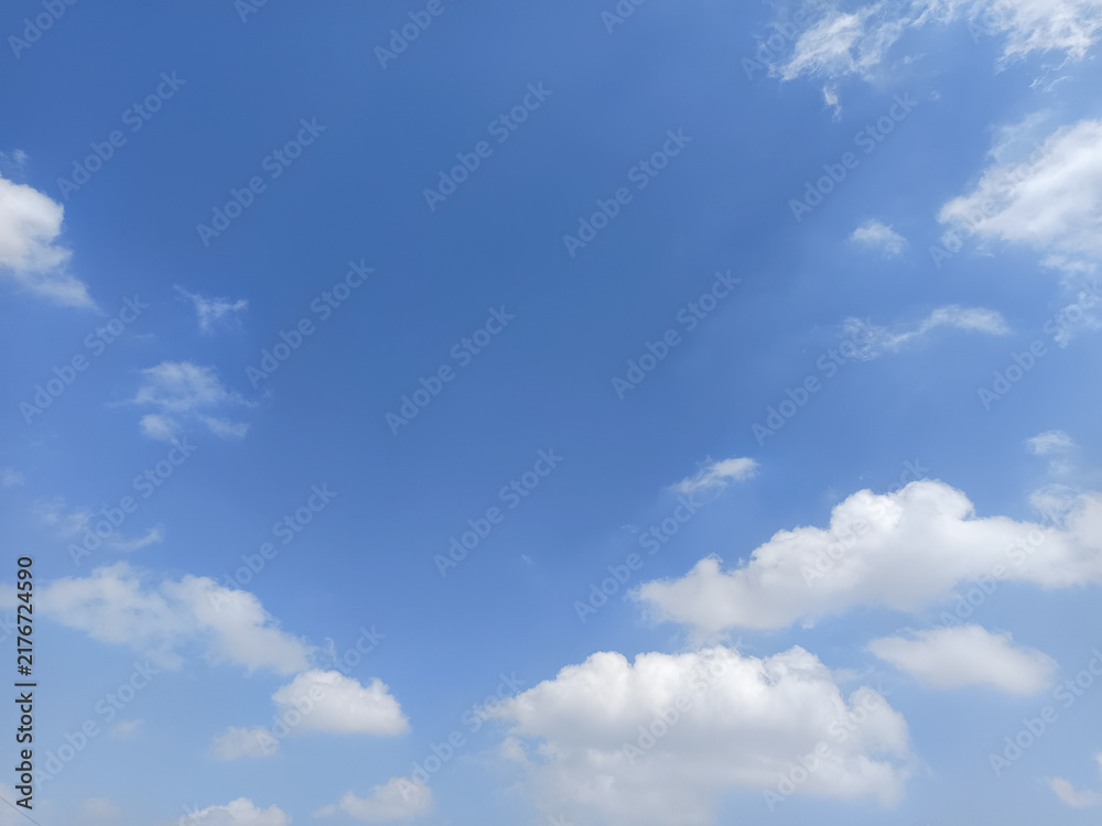 Fototapeta premium Beautiful blue sky with fluffy white cumulus clouds and delicate wispy clouds, creating a peaceful natural background with ample copy space.