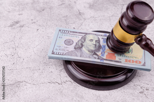 Fotografie Eye level view of a dark mahogany wooden judge gavel crushing one hundred Dollar