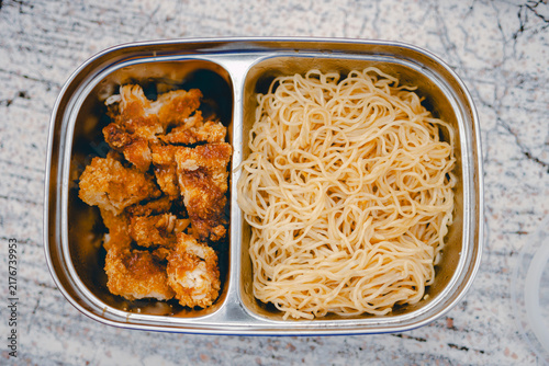 Canvastavla Top-down view of stainless steel bento lunch box filled with yellow noodles and crispy fried chicken pieces with tonkatsu sauce