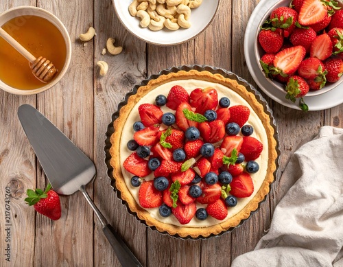 A fruit tart with fresh berries, nuts, and honey. Served with a server on wood