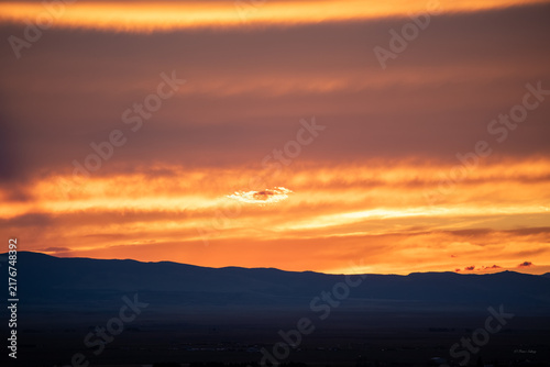 Mountain ridge silhouette under vibrant orange sunrise sky at dawn