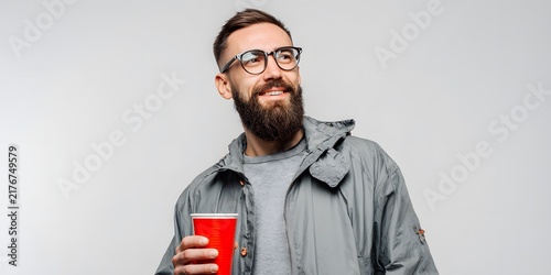 Happy bearded man wearing glasses holding red cup