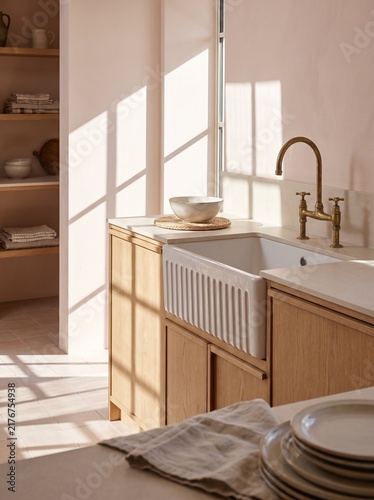 Modern Minimalist Kitchen Interior with Farmhouse Sink, Brass Faucet, and Natural Oak Cabinets in Soft Pastel Pink Light, High-End Home Design Aesthetic with Sunlight Shadows and Ceramic Tableware