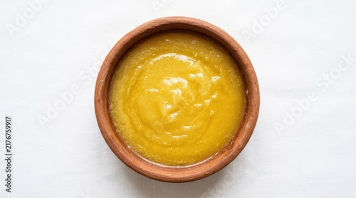 Ghee or clarified butter in a rustic clay bowl isolated on white background