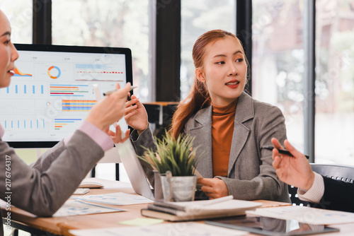 Asian business team analyzing financial data on computer screen in modern office meeting