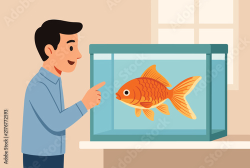Smiling young man pointing finger at large active orange goldfish swimming inside glass aquarium tank at home.