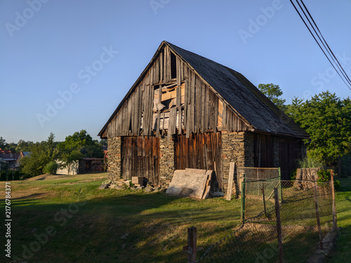 Old weathered wooden barn with stone foundation in a rural countryside landscape