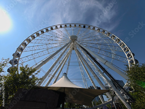 Low angle view of a giant white ferris wheel against a bright blue sky