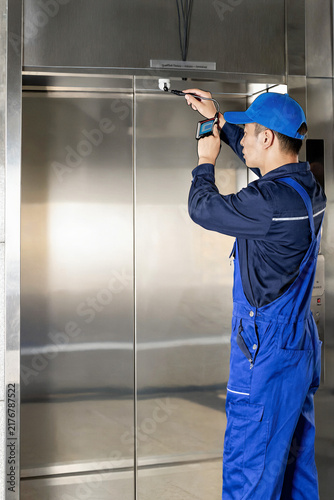 Naklejka Elevator Technician Calibrating Door Sensor