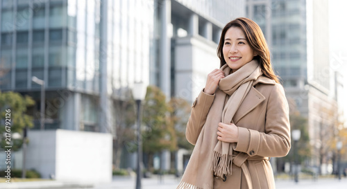 Japanese businesswoman wearing a trench coat and warm scarf walking in city