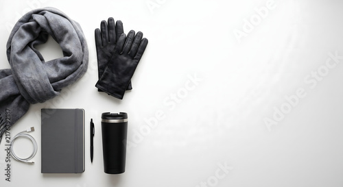 Flat lay of wool scarf leather gloves planner and tumbler on white office desk