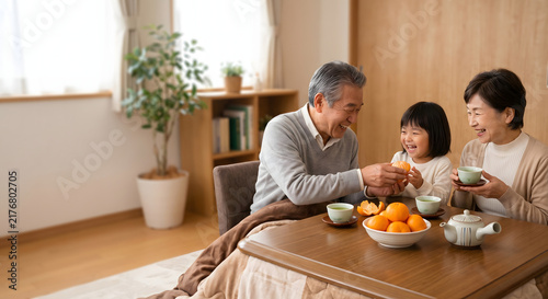 Japanese grandparents and young granddaughter smiling warmly around heated kotatsu table with mandarins and tea