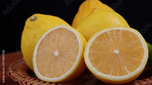 fresh lemons resting on a basket wooden surface. black background