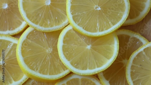 Yellow lemon slices piled togather, close shot. Rotative background. 