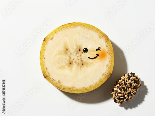 Banana slice with winking face expression and sesame seeds topping isolated on white background for creative food advertising.