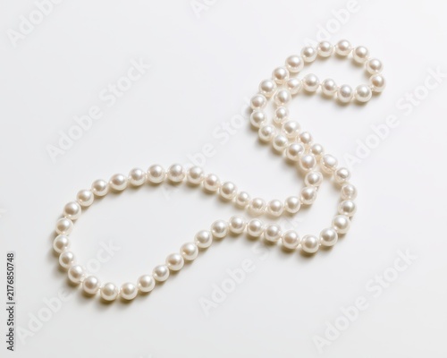 Elegant string of classic white pearls arranged in a graceful curve isolated on white background