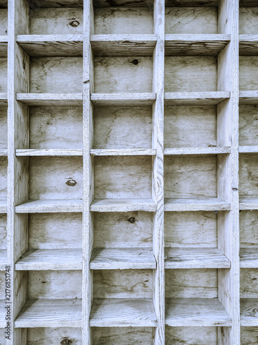 Vintage wooden grid shelves with textured plaster background