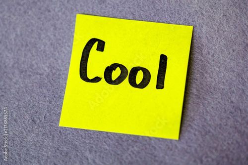 Bright yellow sticky note with handwritten word Cool on grey felt background, positive assessment concept