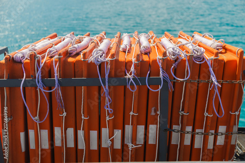 Fotografie Stacked Orange Life Jackets Secured on Ferry Above Turquoise Sea