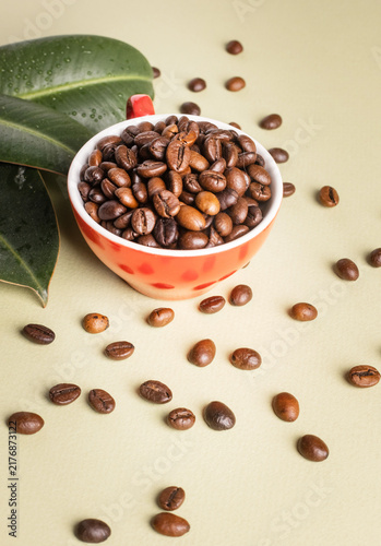 Quadro su tela Red cup with coffee beans on dark surface, minimalist still life.