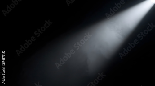 A bright white spotlight beam shining through dark misty air creating a dramatic atmospheric effect on a black background