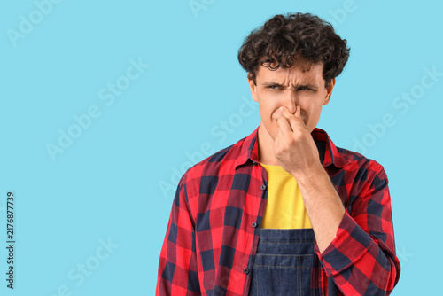Foto Bad smell and disgust, young man pinching nose to block unpleasant odor in studi