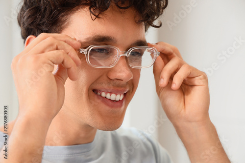 Vision correction and eye health, young man adjusting clear frame glasses for...