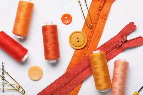 Obraz na plátne Composition with thread spools, zippers and buttons on white background, closeup