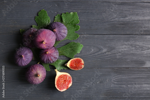Cuadro en lienzo Fresh ripe figs and leaves on black wooden background