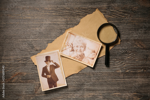фотографія Old photos of relatives with magnifier on wooden background