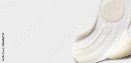 samples of cosmetic care products smear of cream and serum texture on a light background
