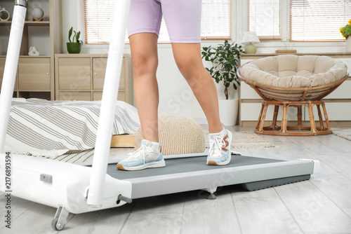 Sporty woman running on treadmill in bedroom