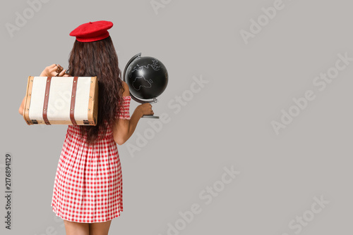 Young Asian woman with globe and suitcase on white background. Travel concept...