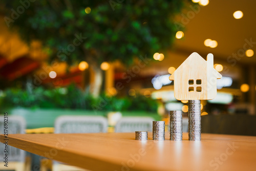 Konstfotografi Real estate and property investment concept with wooden house model on increasing stacks of coins on table for saving money down payment, mortgage home loan and financial growth