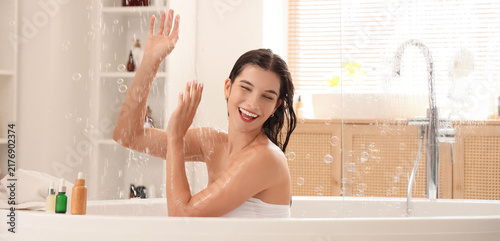 Self care and wellness, happy woman taking a relaxing bath with bubbles and s...