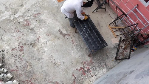 Aerial Drone Shot of Young Metalworker Hammering Welded Metal Sheet