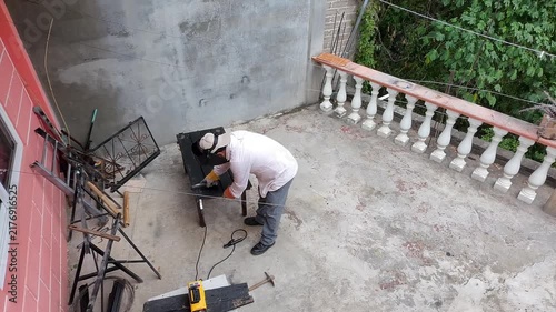 Drone Aerial View of Young Worker Brushing Metal Weld Line with Wire Brush