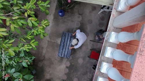 Sunset Aerial Drone View of Young Worker Painting Iron Sheet Black in Yard