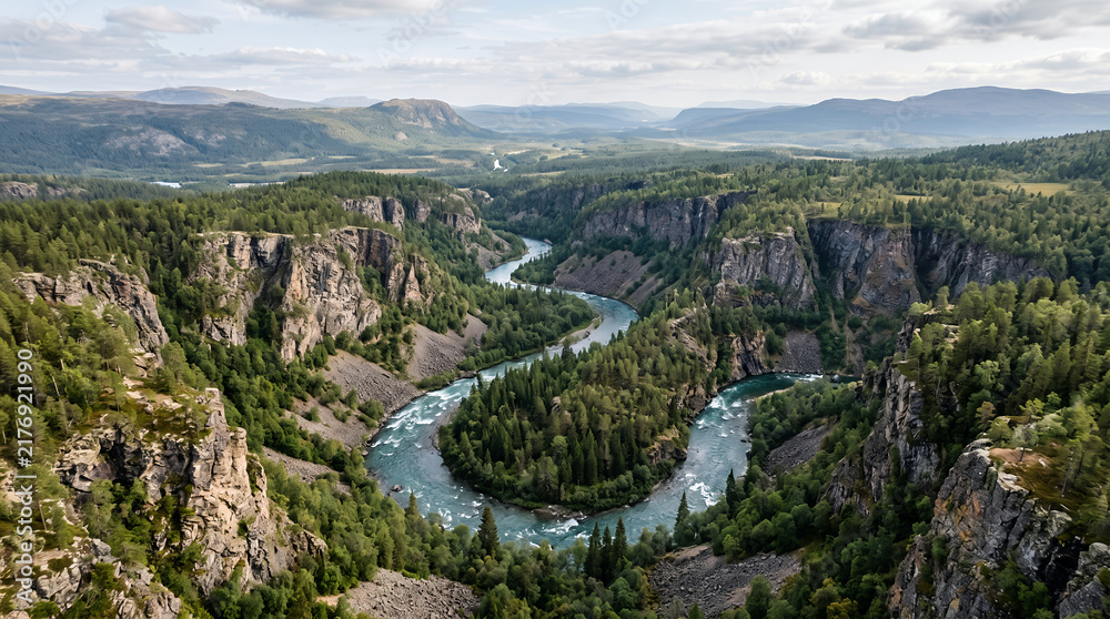 Fototapeta premium River winds through a lush green valley surrounded by steep canyon cliffs.