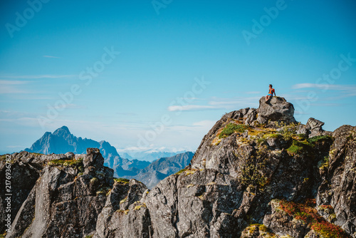 Man sits on rocky peak admiring mountain view