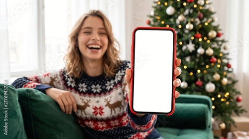Happy young woman holding mobile phone in hand showing cellphone display, presenting big white blank cellular display template mock up, red smartphone mockup screen for shopping christmas, promo ads.