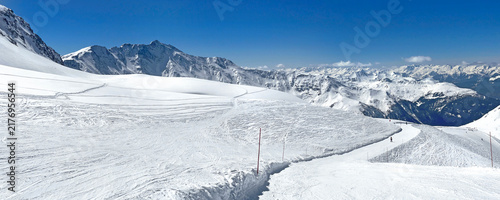 panorama on ski resort in tarentaise valley, savoie with snowy mountain range and ski slope under blue sky